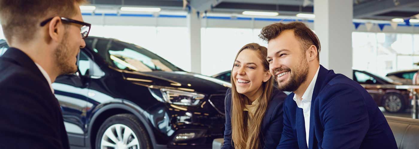 Couple at car dealership speaking to sales