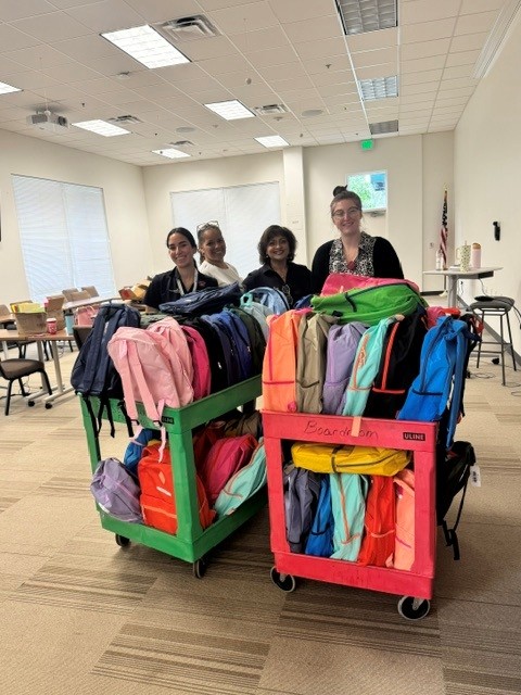 team members with 2 full carts fill with backpacks