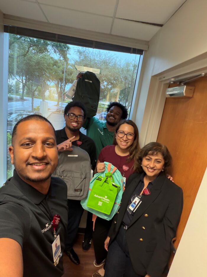 team members selfie holding backpacks